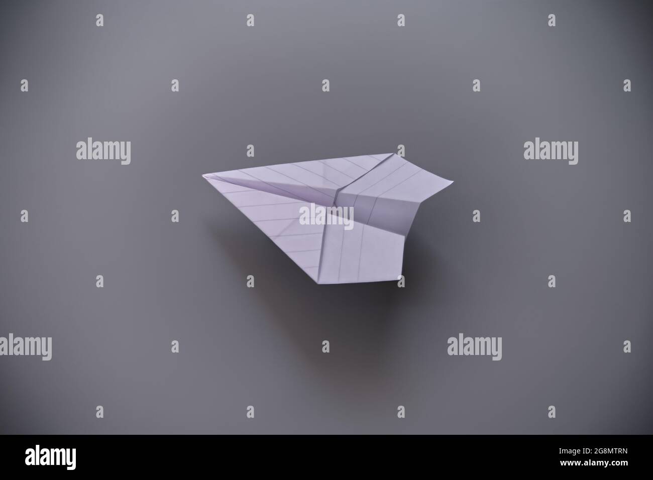 White paper airplane against a gray background Stock Photo