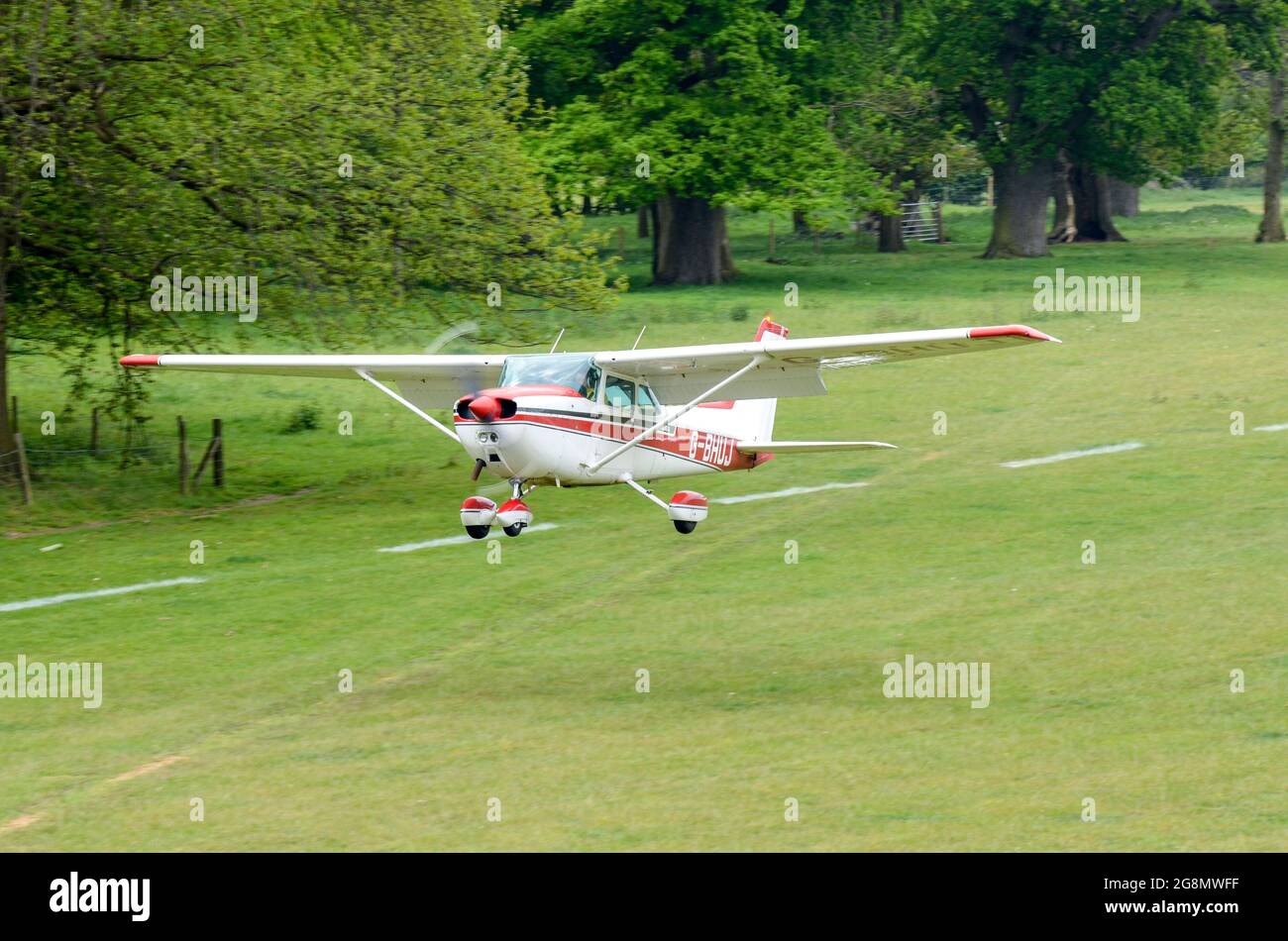 Cessna 172 Skyhawk plane taking off from a grass strip in a wooded, rural area. Henham Park temporary grass strip for country event Stock Photo