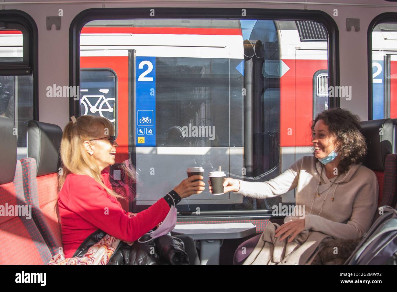 Happy women traveling by train making a toast with coffee and having fun. Stock Photo