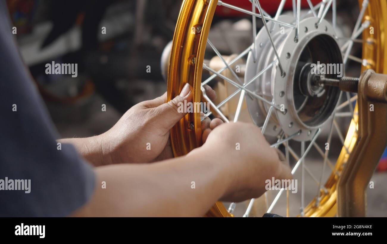 Technician man working motorcycle wheel has spokes weave up on mechanic