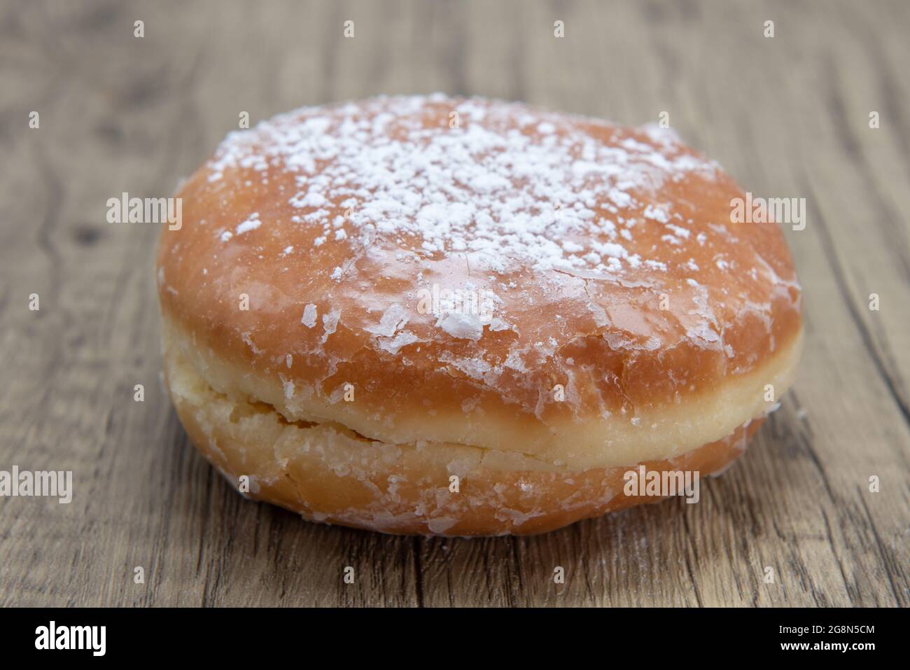 Lemon filled glazed donut is textured with powdered sugar coating for a sweet treat delight. Stock Photo