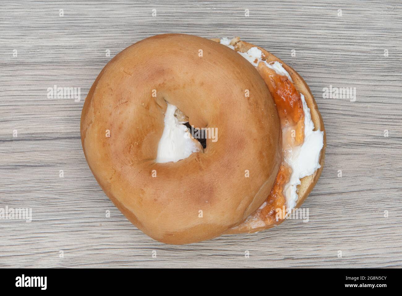 Overhead view of cream cheese and jelly bagel cut in half and ready to eat for breakfast. Stock Photo