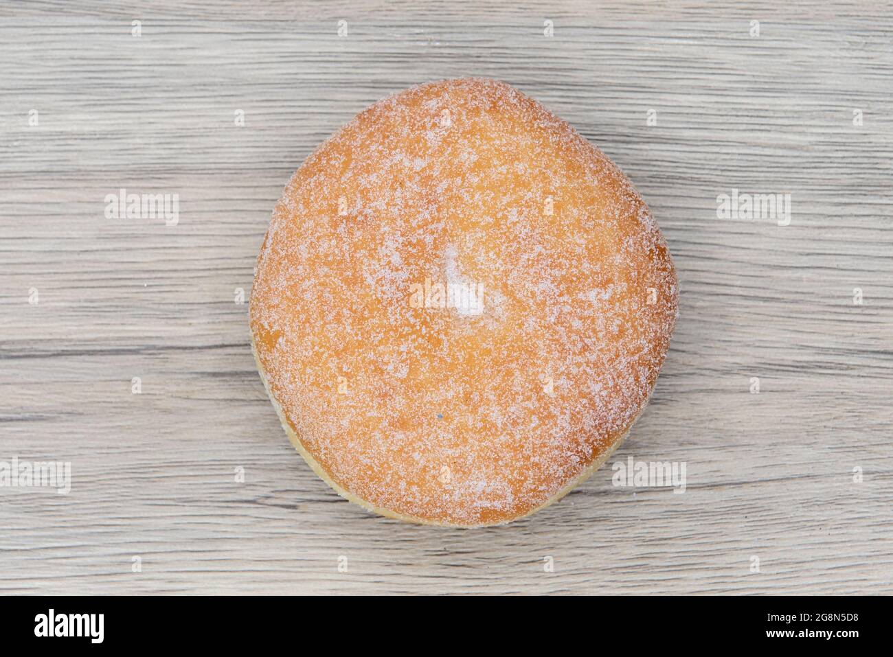 Overhead view of sugar raised round donut is textured with sugar coating for a sweet treat delight. Stock Photo
