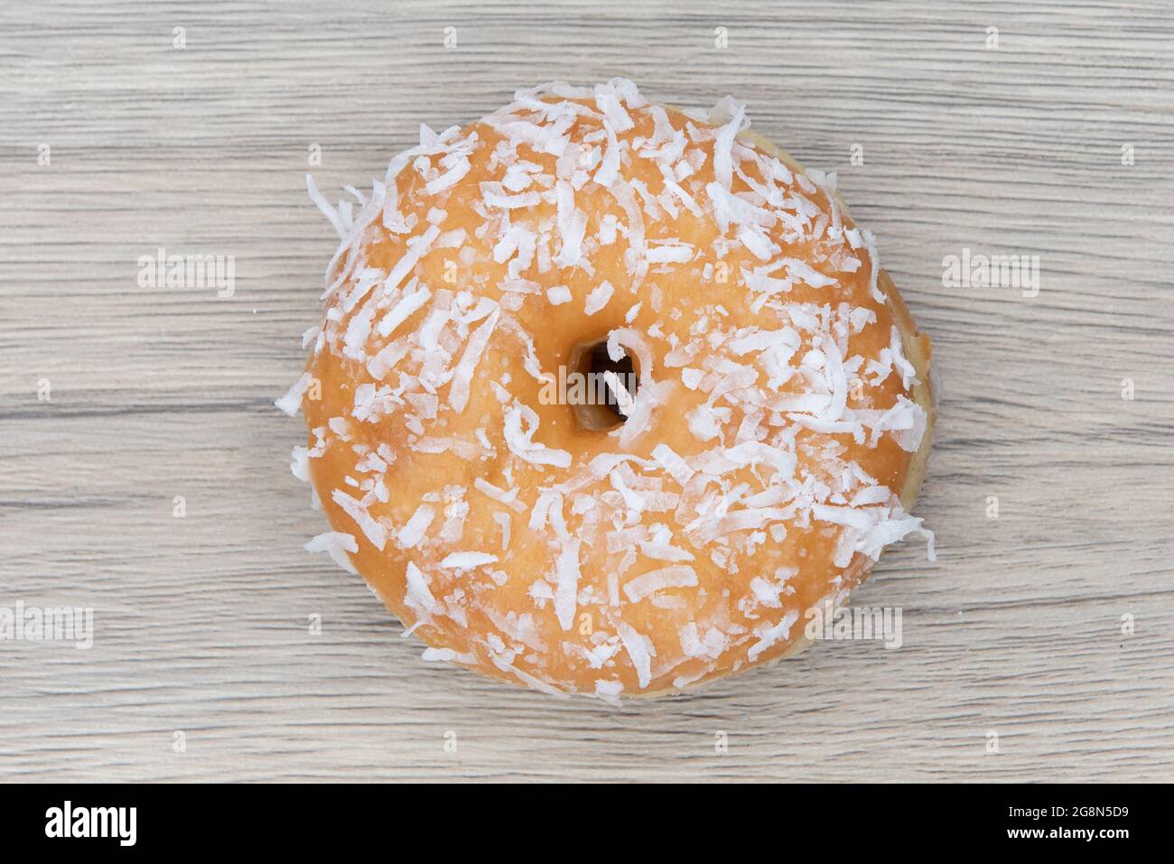 Overhead view of cocnut raised  donut is textured with glazed coating for a sweet treat delight. Stock Photo