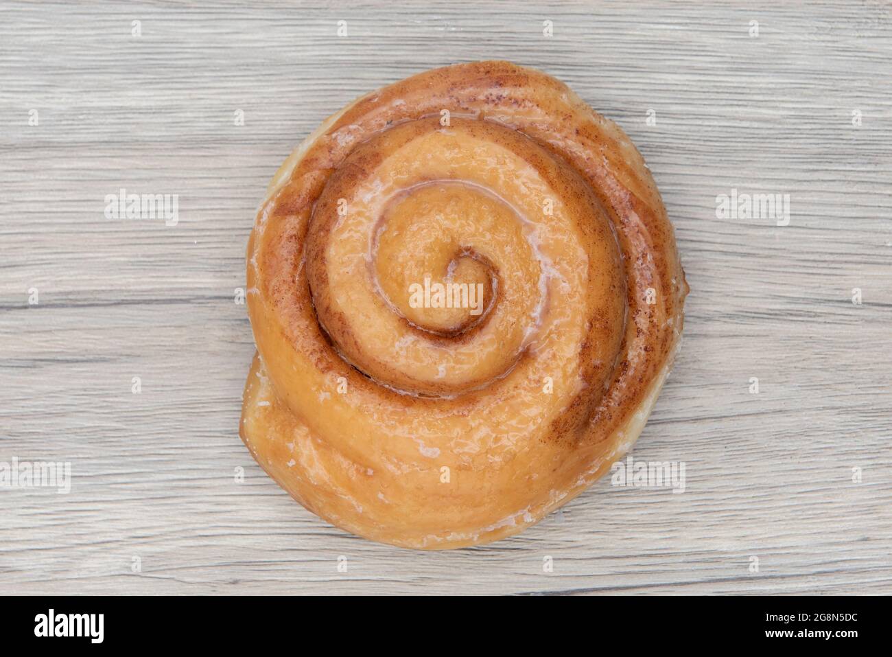 Overhead view of cinnamon roll donut is textured with glazed coating for a sweet treat delight. Stock Photo