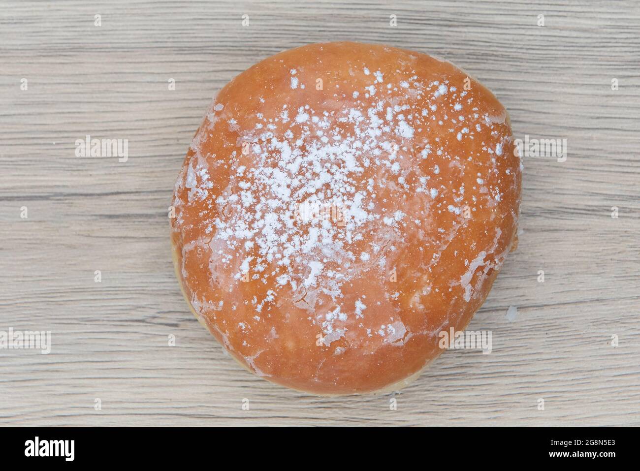Overhead view of lemon filled glazed donut is textured with powdered sugar coating for a sweet treat delight. Stock Photo