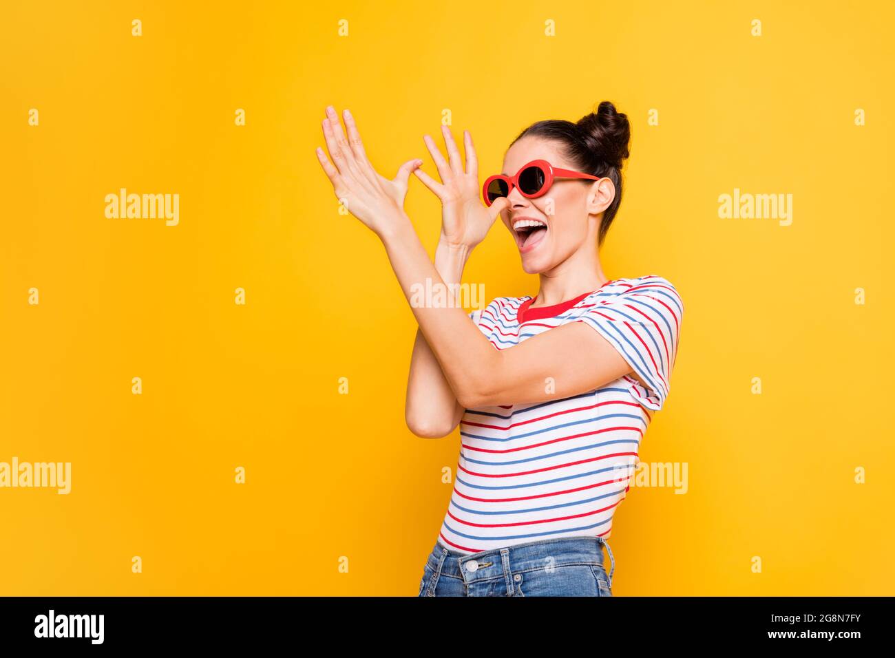 Photo of adorable funky young girl dressed striped t-shirt dark glasses dancing arms nose isolated yellow color background Stock Photo