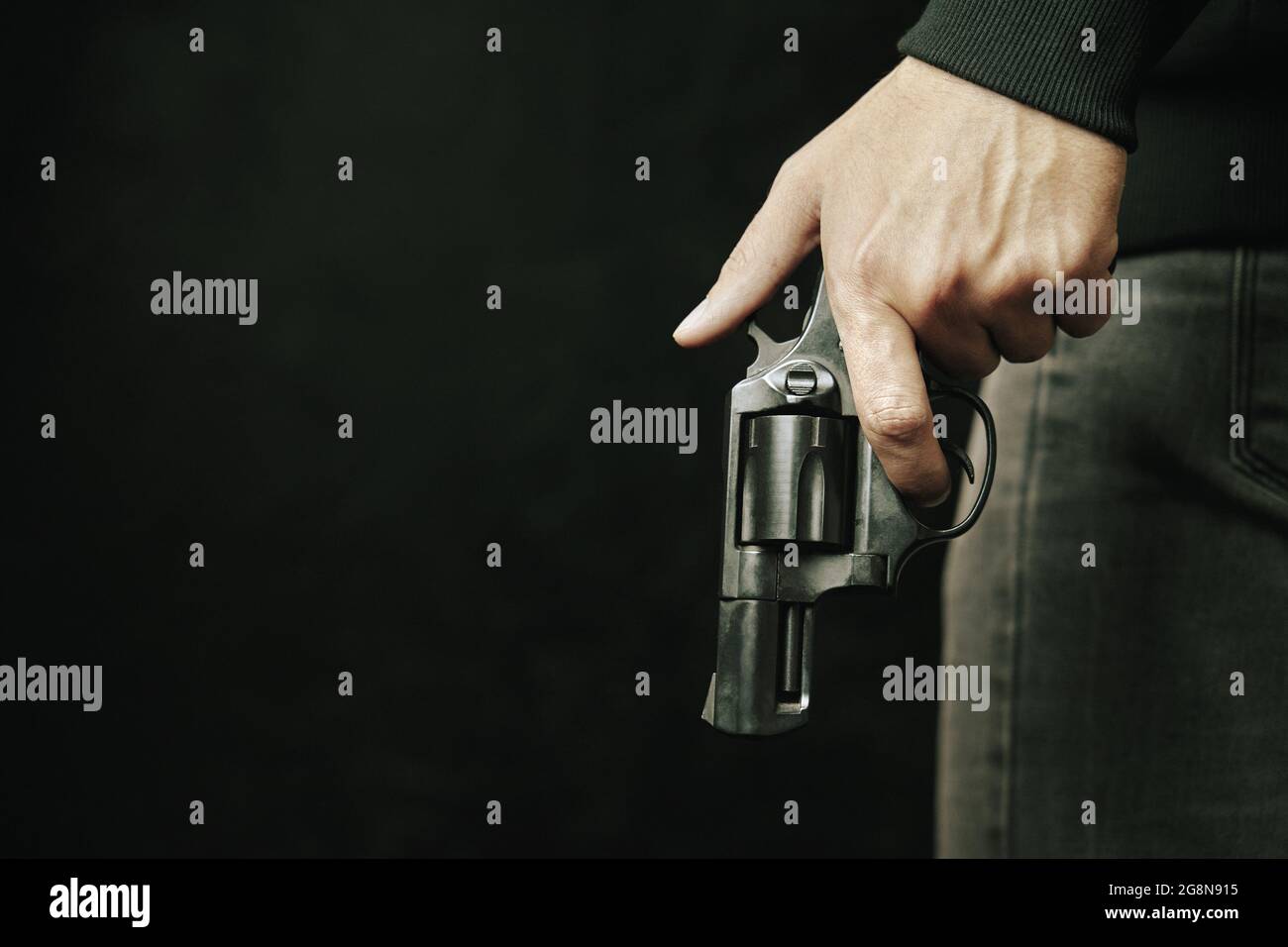 Guy with gun down. Black revolver with drum in man's hand. Armed person