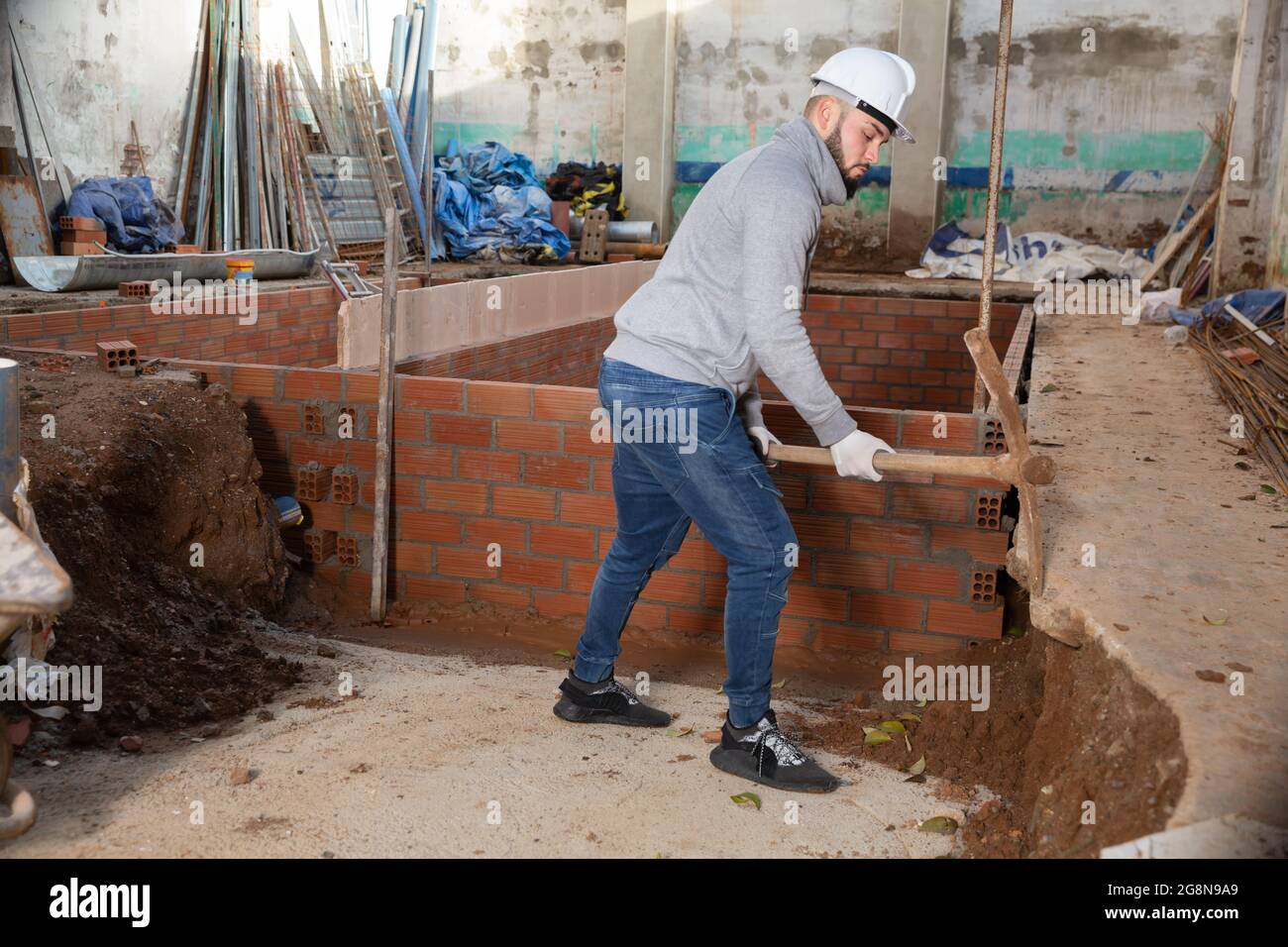 Guy excavating ground with mattock at building site Stock Photo Alamy