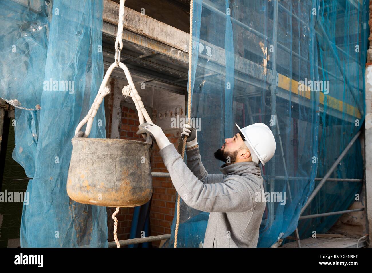 Worker lifting bucket with cement mortar Stock Photo Alamy