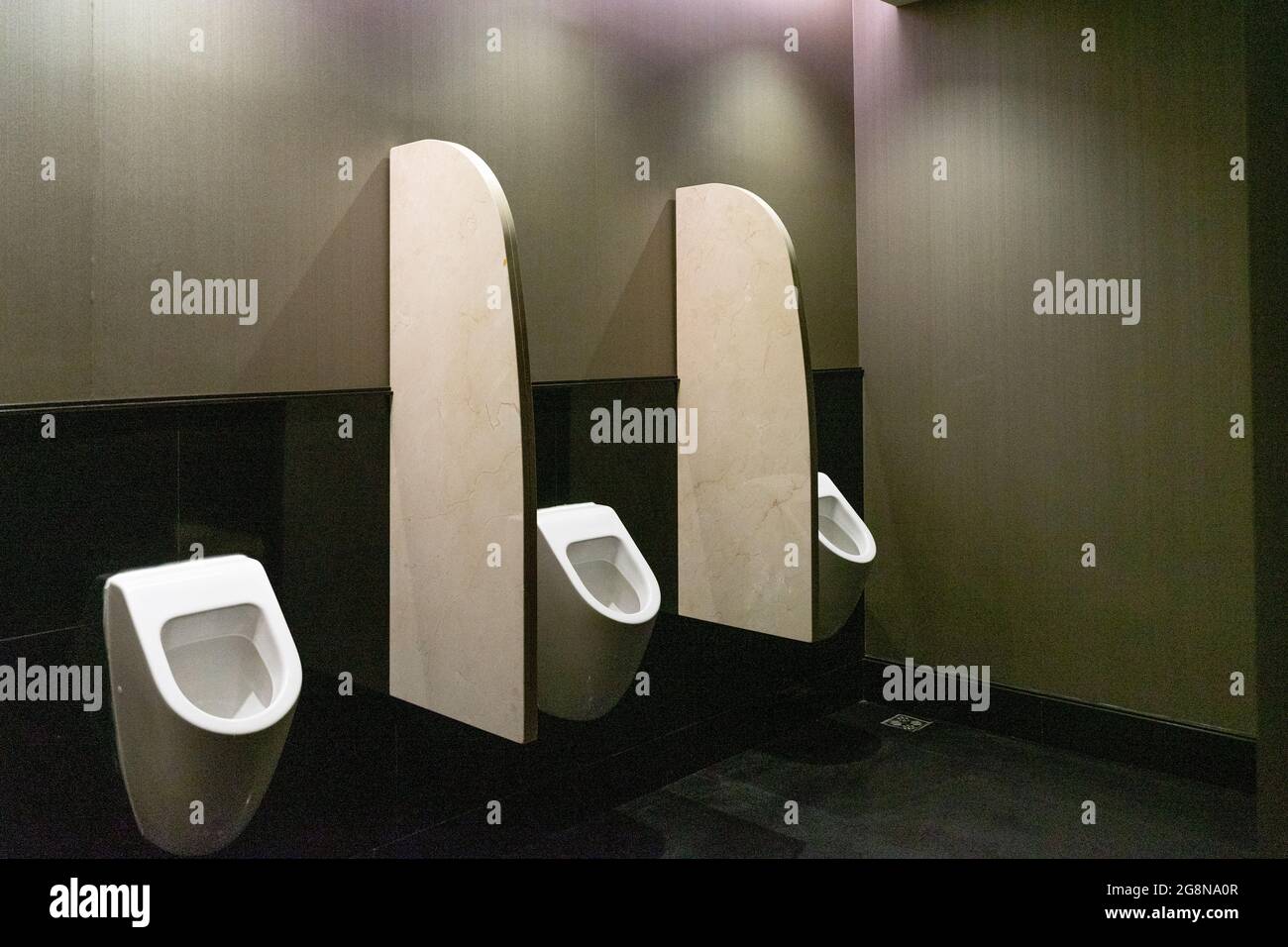 https://c8.alamy.com/comp/2G8NA0R/three-white-mens-urinals-in-a-bathroom-in-lobby-of-luxurious-hotel-2G8NA0R.jpg