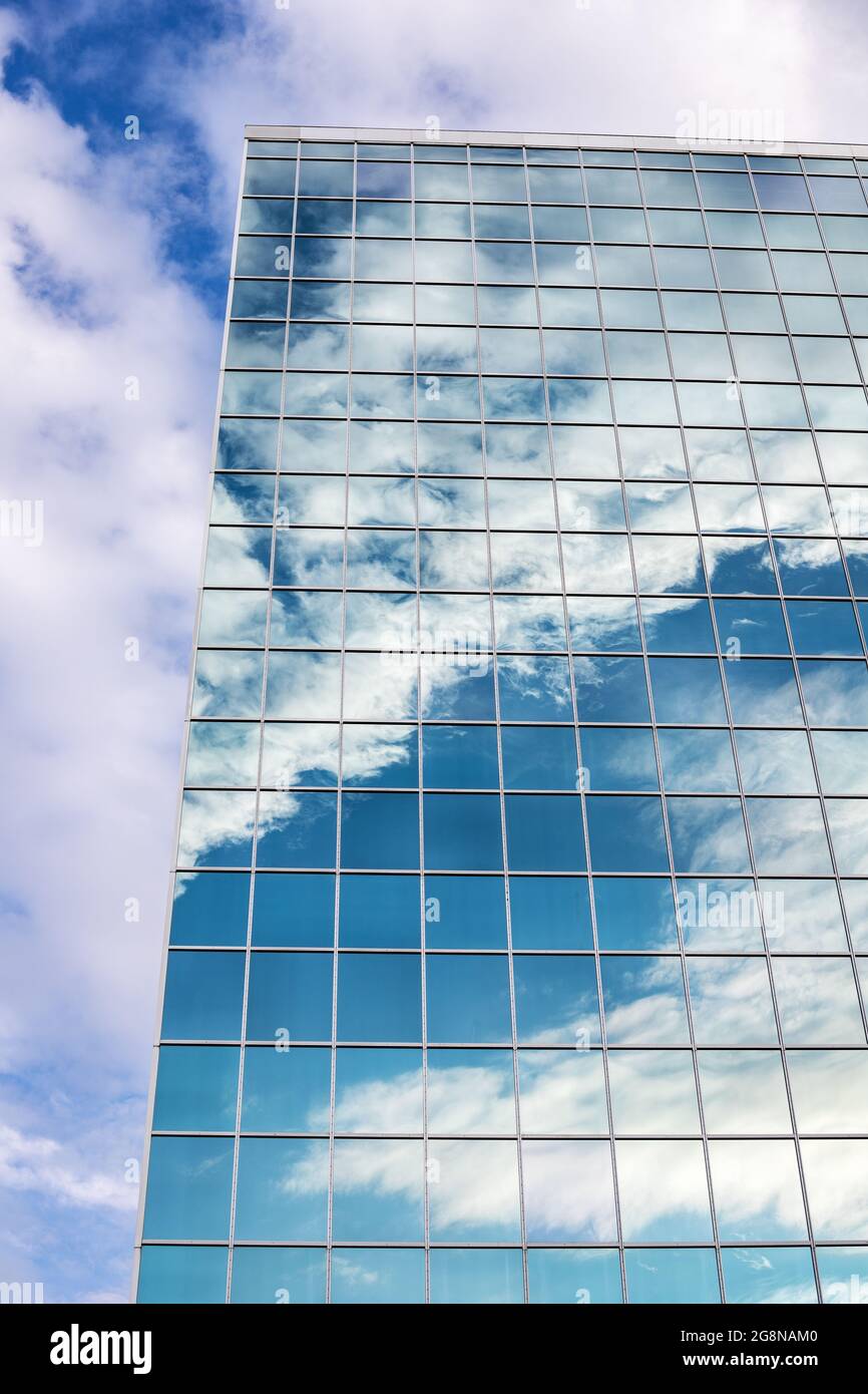 Reflection of blue sky with clouds in tall modern glass building in ...