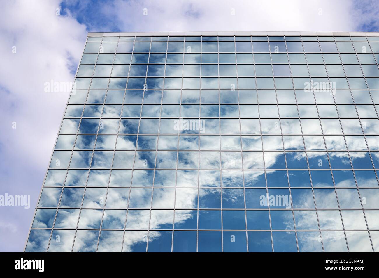 Reflection of blue sky with clouds in tall modern glass building in ...