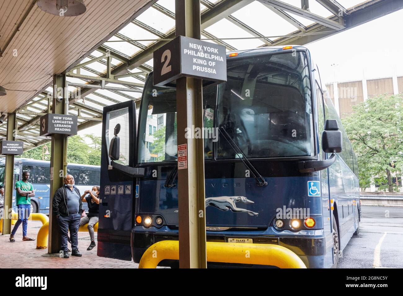 Passengers at Greyhound bus terminal wait for a mechanic to fix a bus's