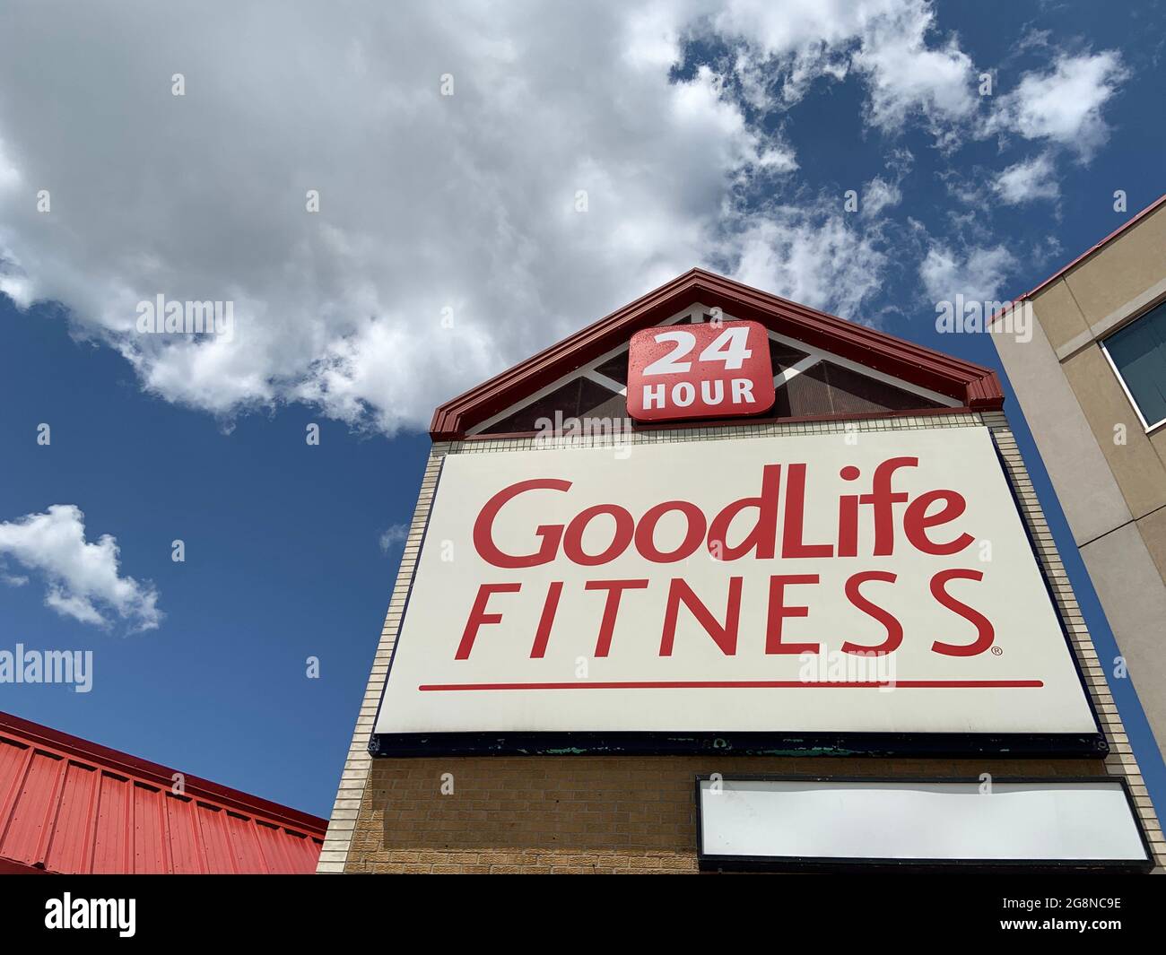 A sign on a building with Goodlife Fitness and blue sky background. Goodlife Fitness is a 24 hr gym and health club. Stock Photo