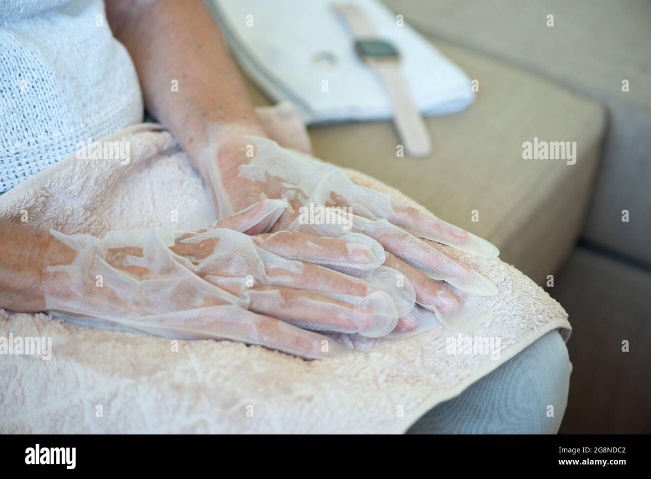 Senior woman wearing hand mask gloves. Moisturizing gloves to soften and protect hand skin. Hands close up. Stock Photo