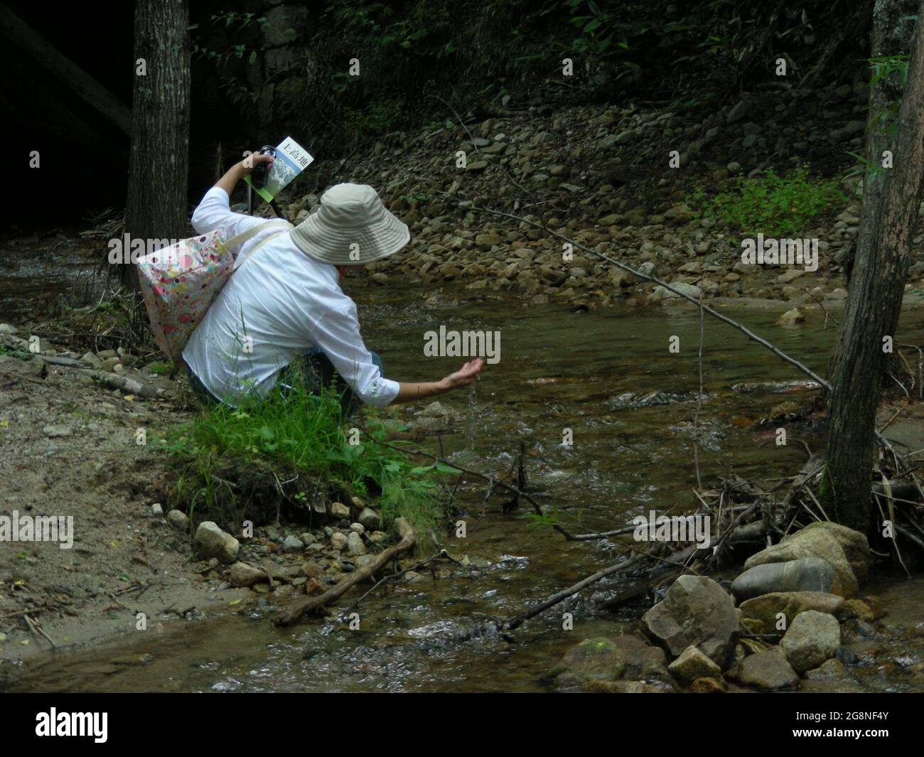 Woman touching water of the Azusa river in Kamikochi Stock Photo