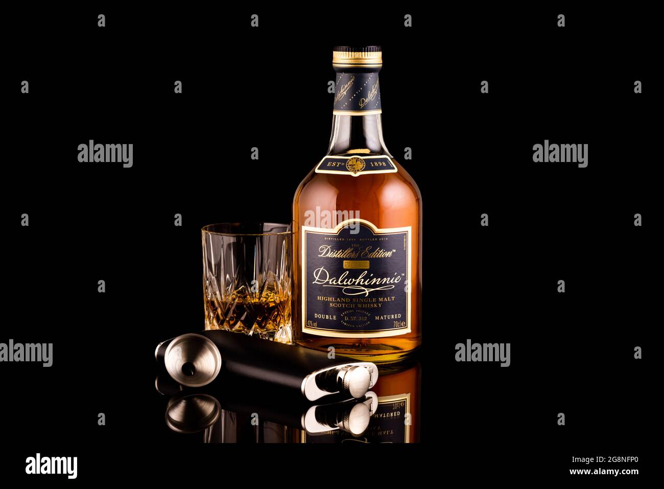 LISSE, THE NETHERLANDS - JULY 15, 2021: Dalwhinnie Distillers Edition bottle and a glass and black hip flask of scotch single malt whisky on a reflect Stock Photo