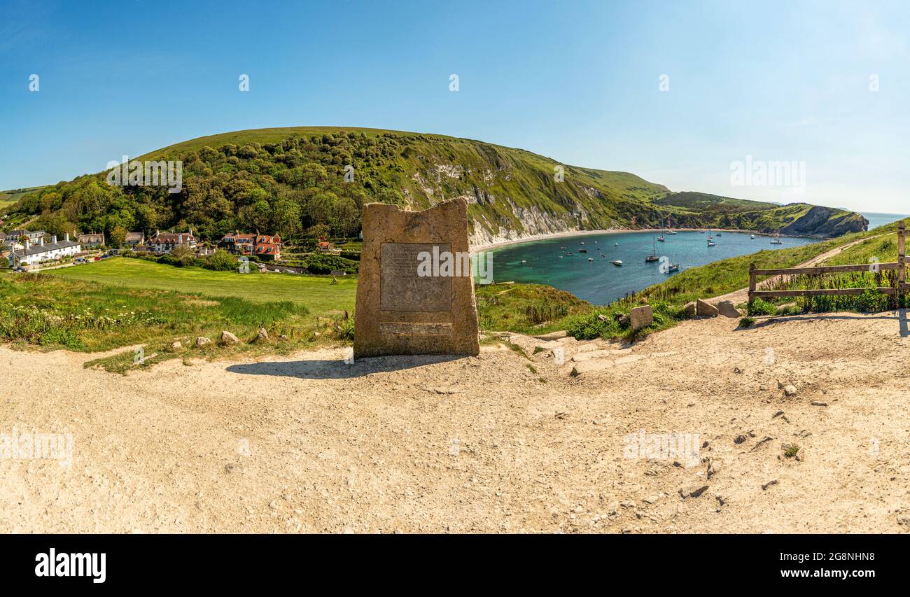 Lulworth Cove World heritage commemorative stone at the viewpoint on a bright hot summer's day with SW coastal path in the distance on the clifftop. Stock Photo