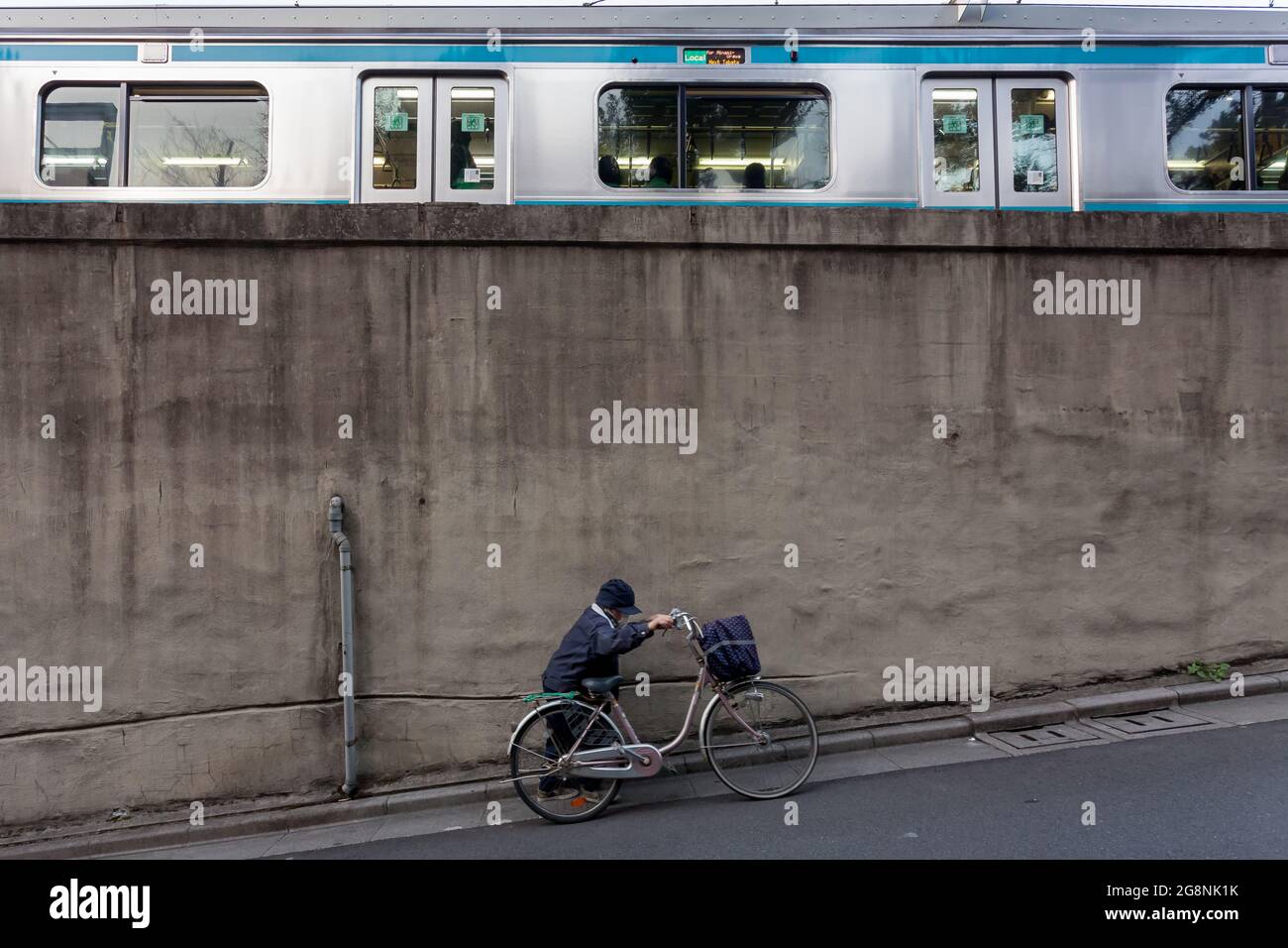 An older Japanese woman pushes her bicycle up a slope by Nishi Nippori station.Tokyo, Japan. Stock Photo