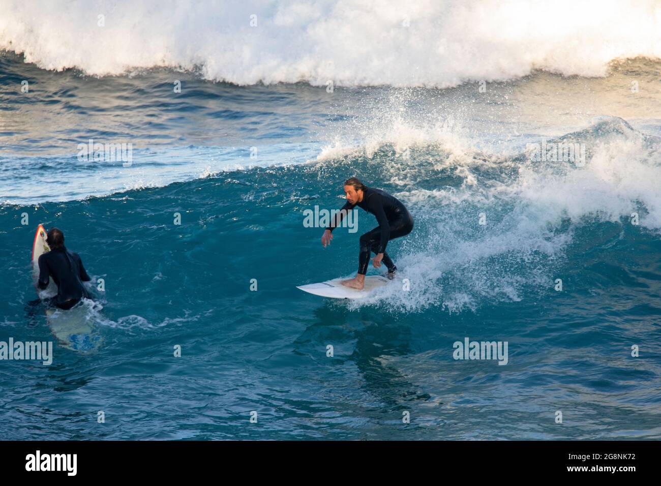 Male surfer in a wetsuit surfing off the coast of Avalon Beach in