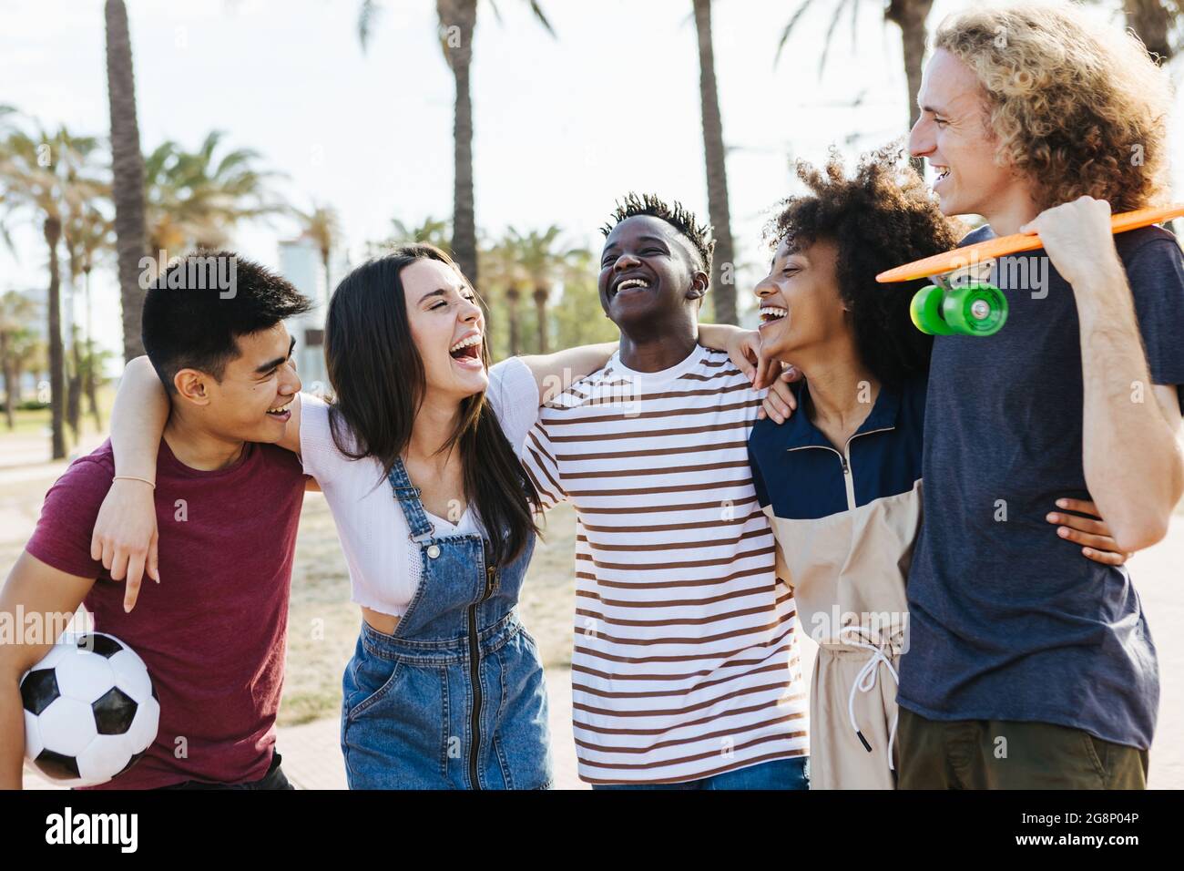 Happy friends from diverse cultures and races laughing and having fun at public park - Multi-ethnic group of young people enjoying on summer holidays Stock Photo