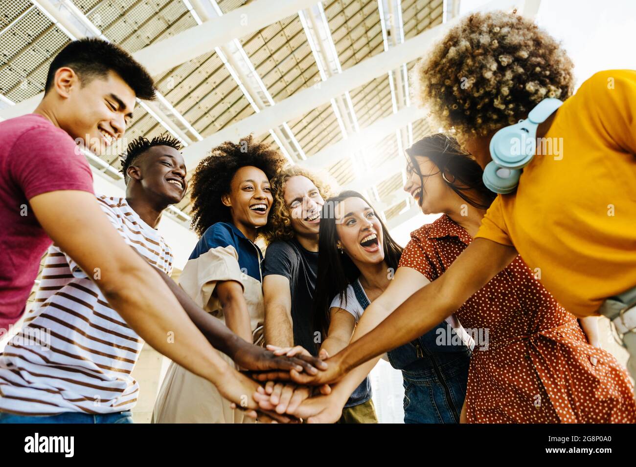 Multiracial happy friends with hands in stack. Multi-ethnic diverse group of college students joining their hands.  Stock Photo