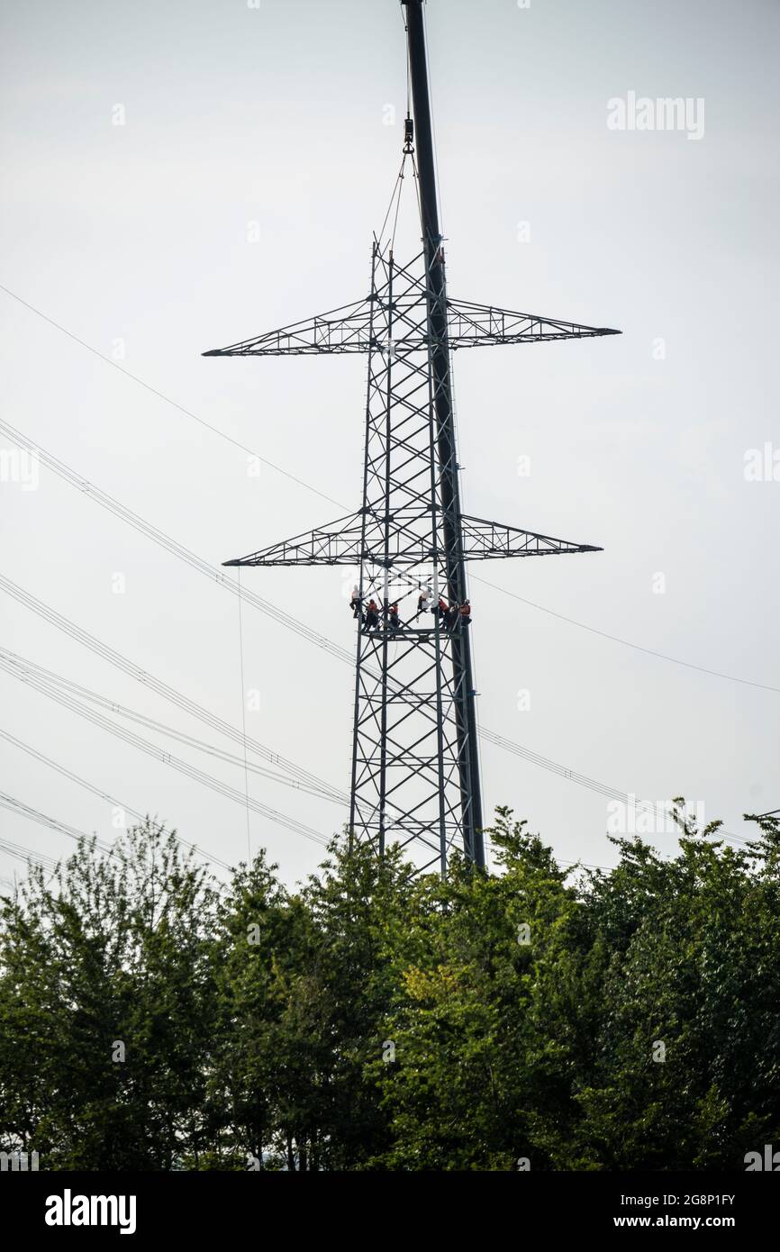 Auf einem Feld zwischen Kaarst und Düsseldorf bauen Mitarbeiter der Firma SPIE Leitungsbau einen Elektrizitätsmast auf. Wie Playmobil-Männchen sehen d Stock Photo