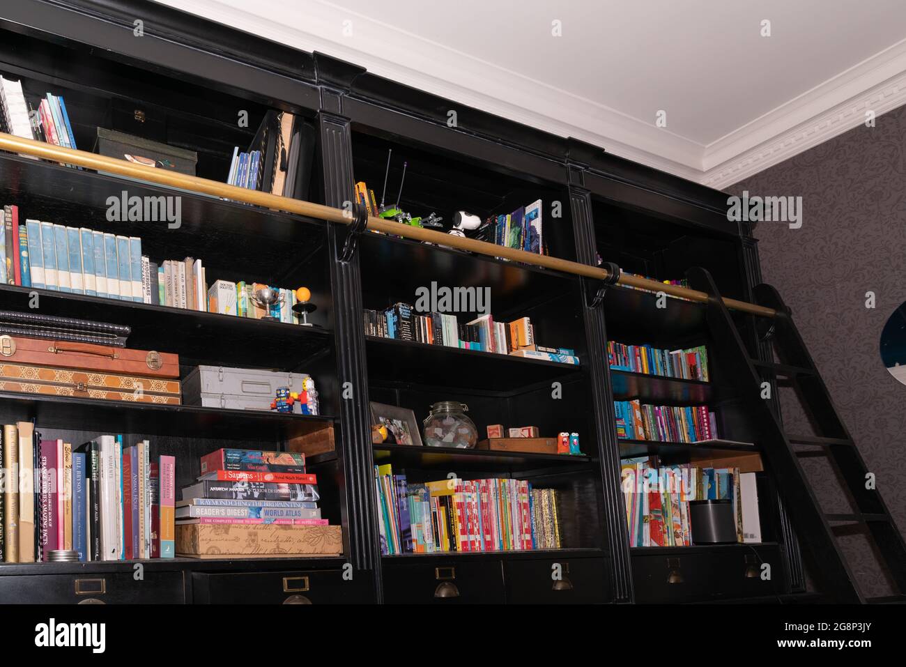 Auckland New Zealand 19 July 2021; Dark timber bookshelf crammed with books and items for a