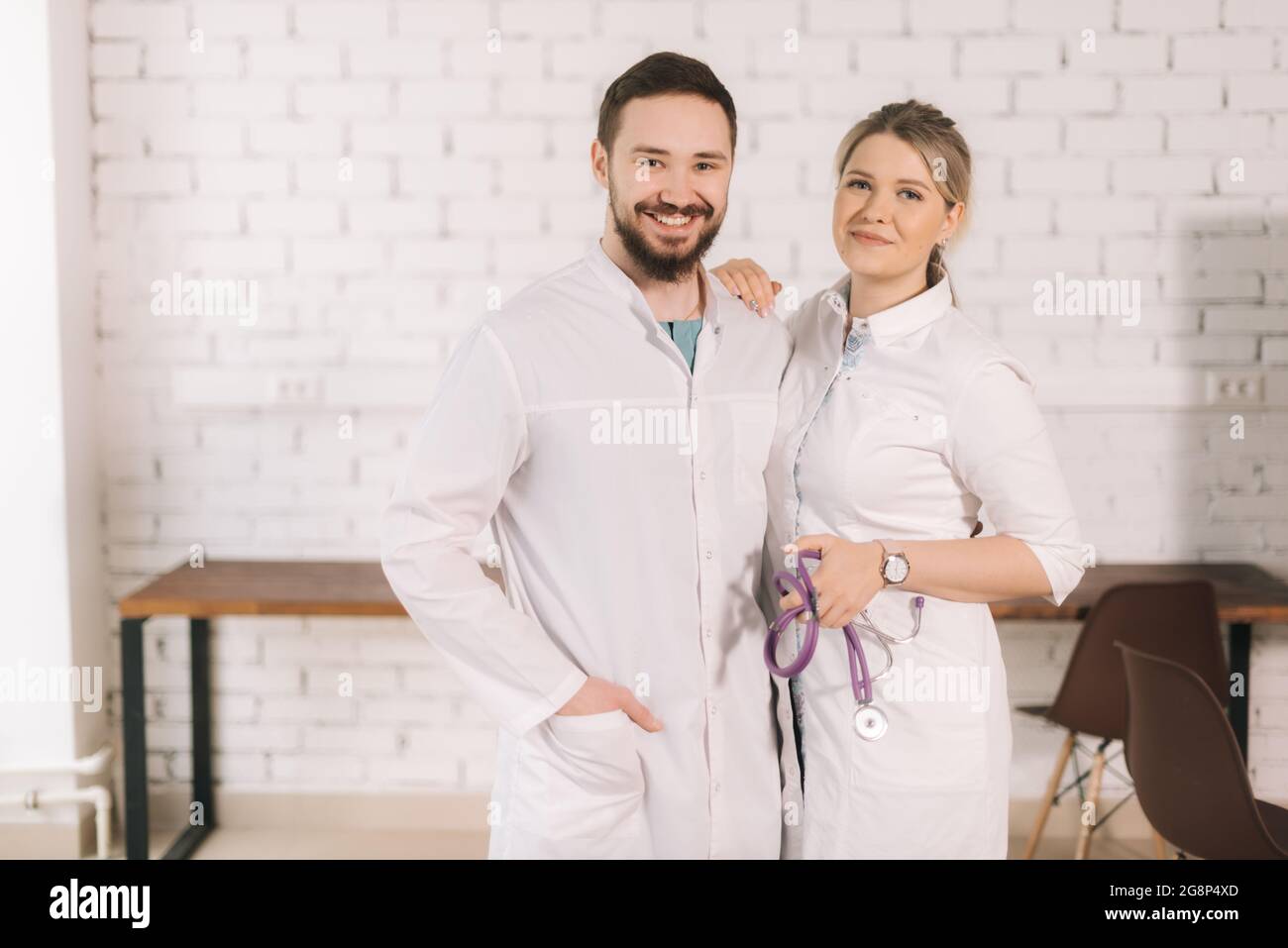 Portrait of two cheerful successful doctors wearing white lab coat