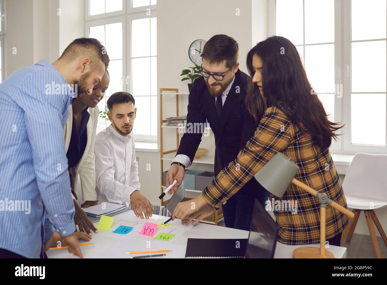 Business team writes notes on colored sticky stickers while discussing a startup project. Stock Photo