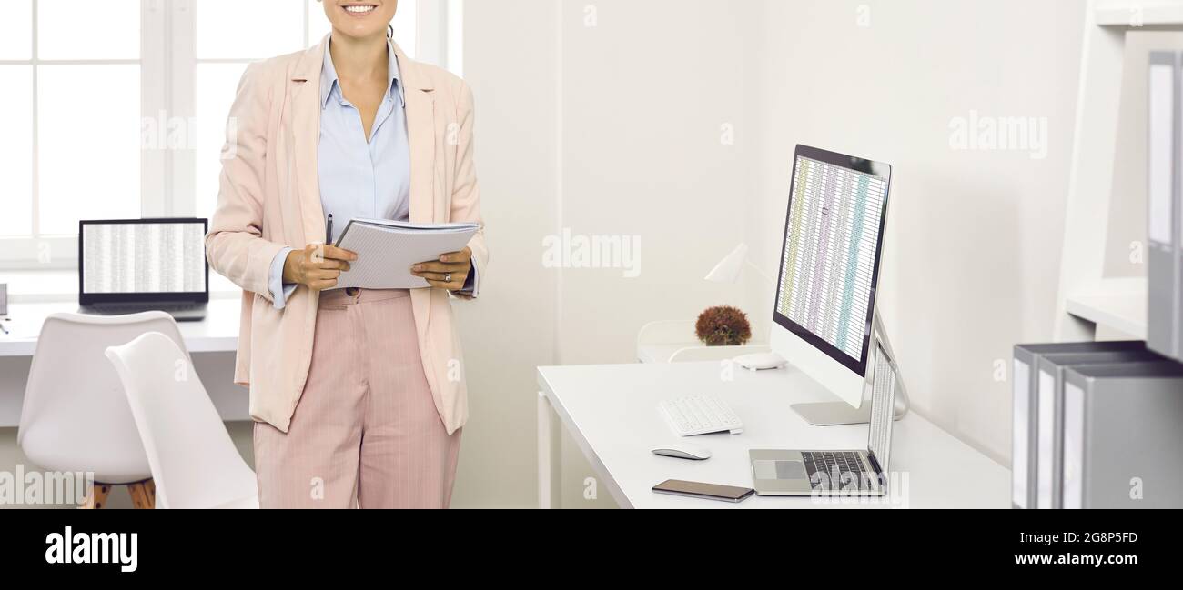 Accountant Woman with no face in the office of an audit company. Accounting. Banner with cropped shot of happy business woman in office with desktop Stock Photo