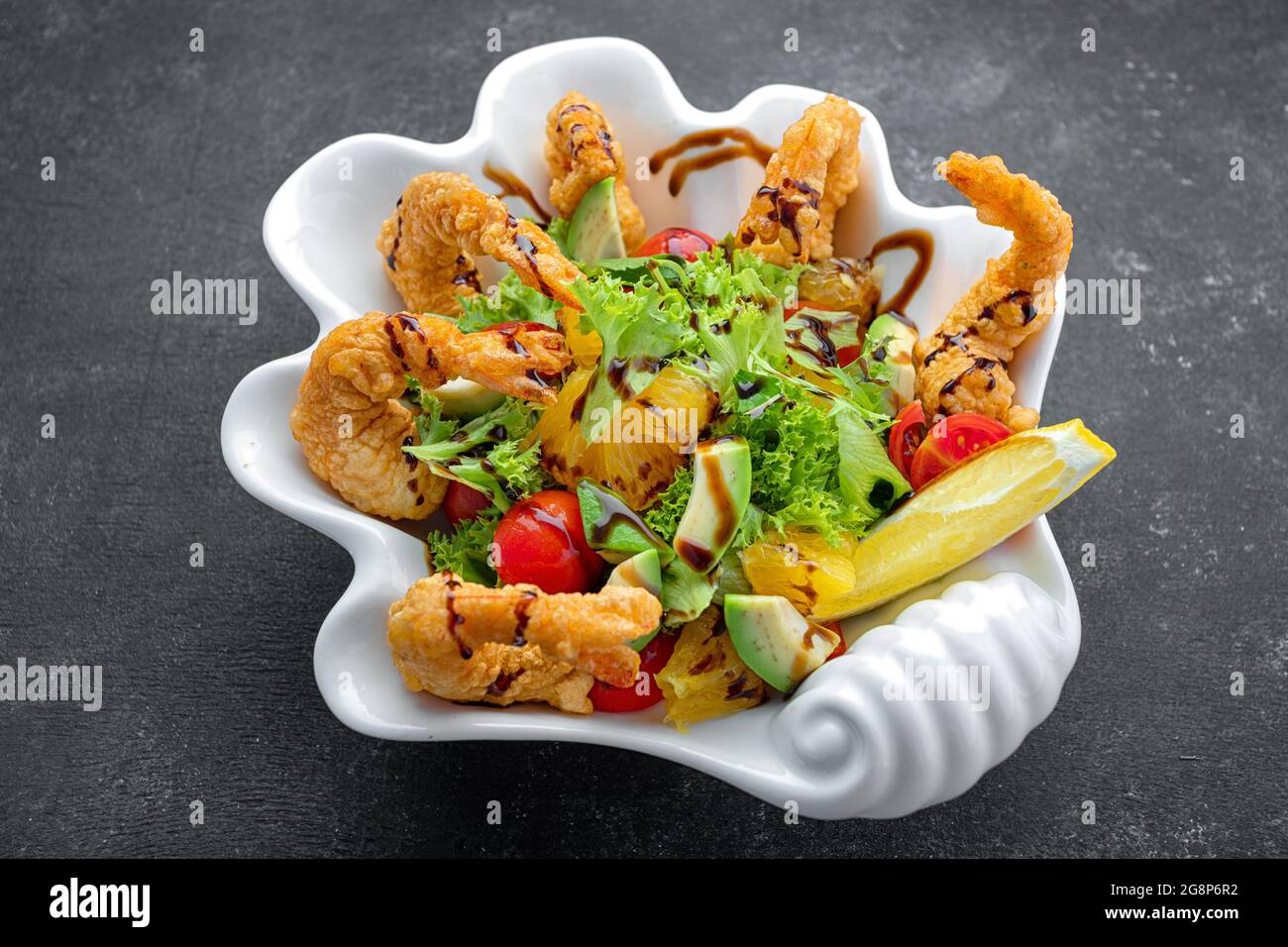 Japanese Cuisine - Tempura Shrimps shrimp in tempura with lemon slices and salad on a black background Stock Photo