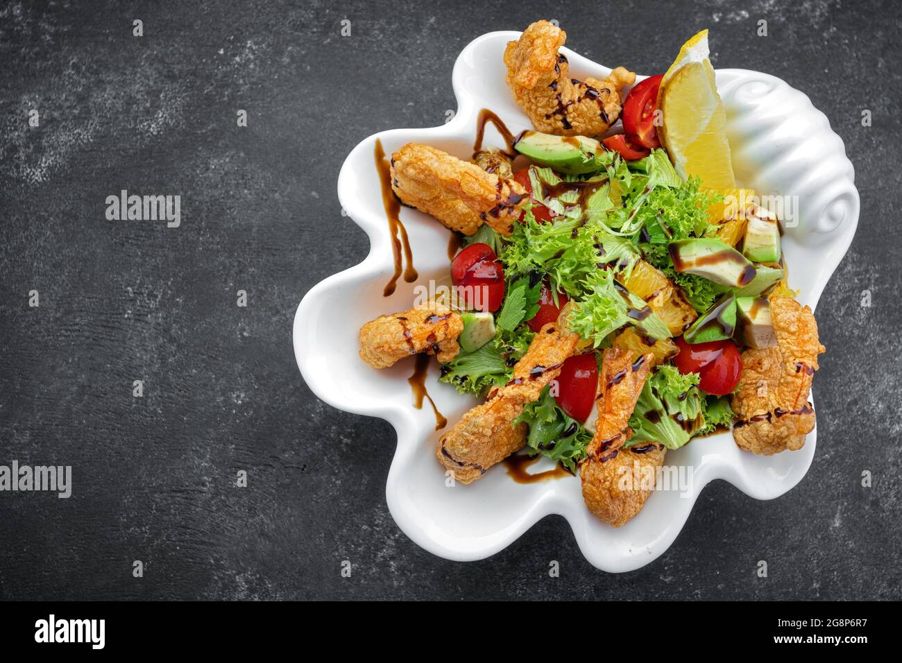 Japanese Cuisine - Tempura Shrimps shrimp in tempura with lemon slices and salad on a black background Stock Photo