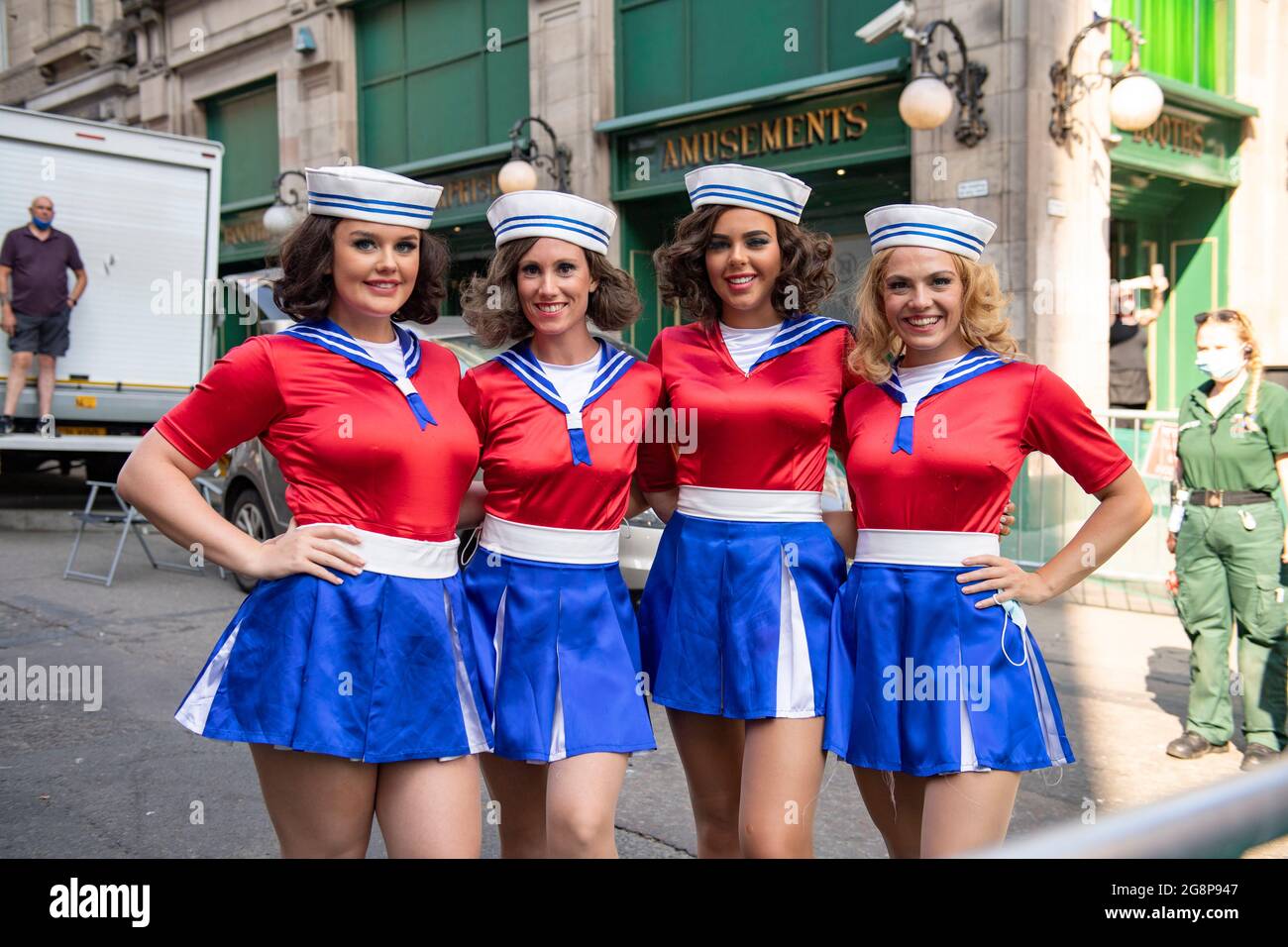 Glasgow, Scotland, UK. 21 July 2021.  PICTURED: A group of cheerleaders seen taking a break in between takes on the film set. Filming on the set of Indiana Jones 5 in the middle of Glasgow city centre as the Hollywood blockbuster sets up Glasgow as New York City. A full production can be seen, with a large cast, producers and extras. The city centre has been changed so that all the shop fronts and building look like 1959 America. Credit: Colin Fisher Stock Photo