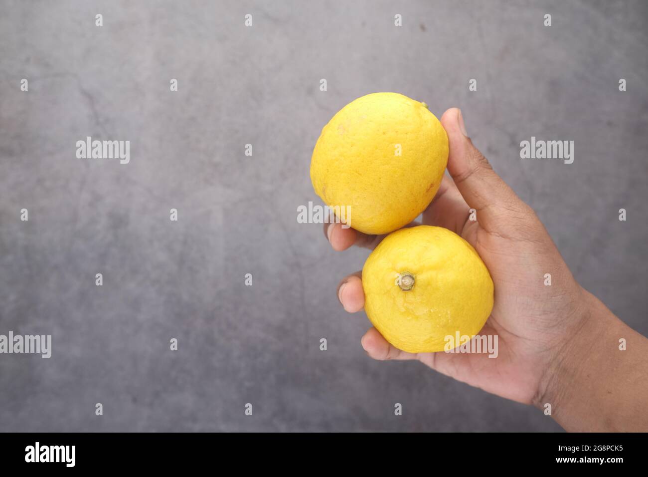 holding Yellow Lemon on black background  Stock Photo