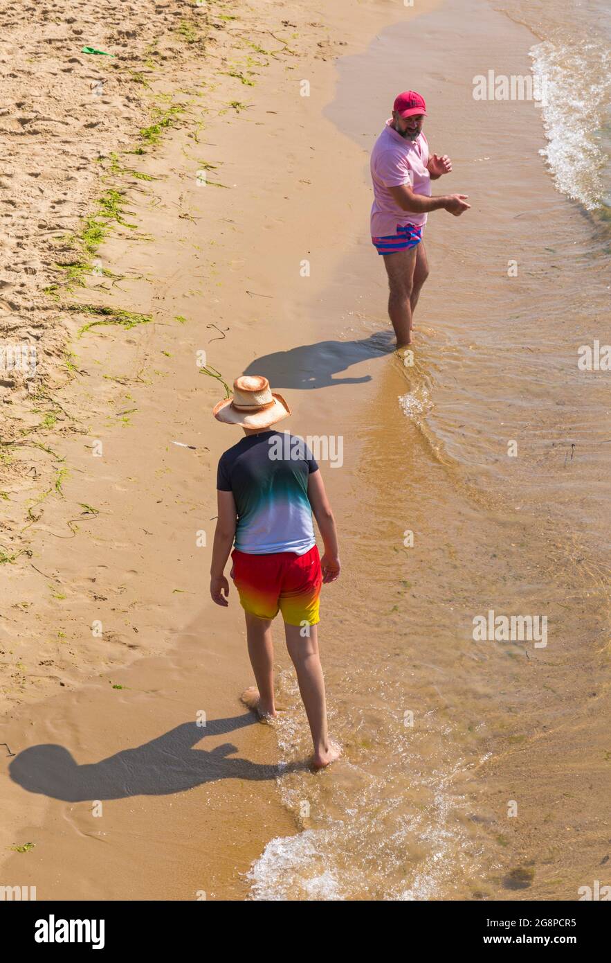 Bournemouth, Dorset UK. 22nd July 2021. UK weather: another hot, sunny and humid day at Bournemouth beaches as the heatwave continues and sunseekers head to the seaside to enjoy the sunshine.  Two men on the seashore. Credit: Carolyn Jenkins/Alamy Live News Stock Photo