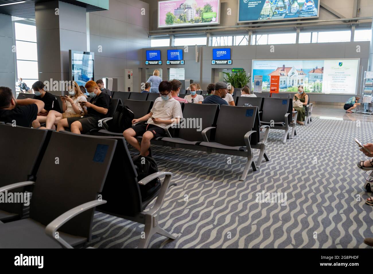 Ukraine, Odessa - July 16, 2021: Odessa airport. Inside the terminal before the flight. Odesa ODS Airport. Masked people are waiting to board the plane. Travelers at the airport in the waiting room. Stock Photo
