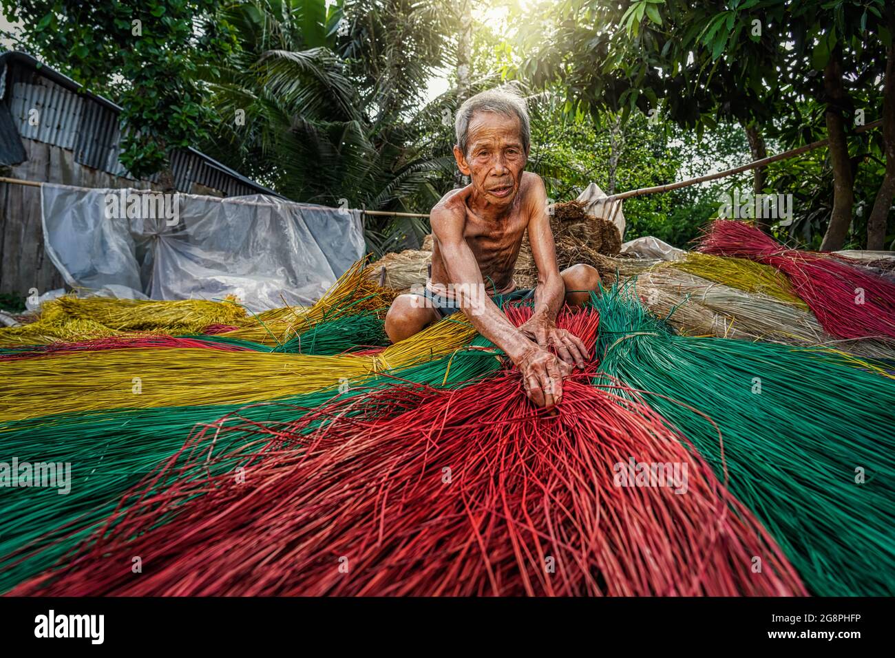 Vietnamese Old man craftsman making the traditional vietnam mats in the old traditional village at dinh yen, dong thap, vietnam, tradition artist conc Stock Photo