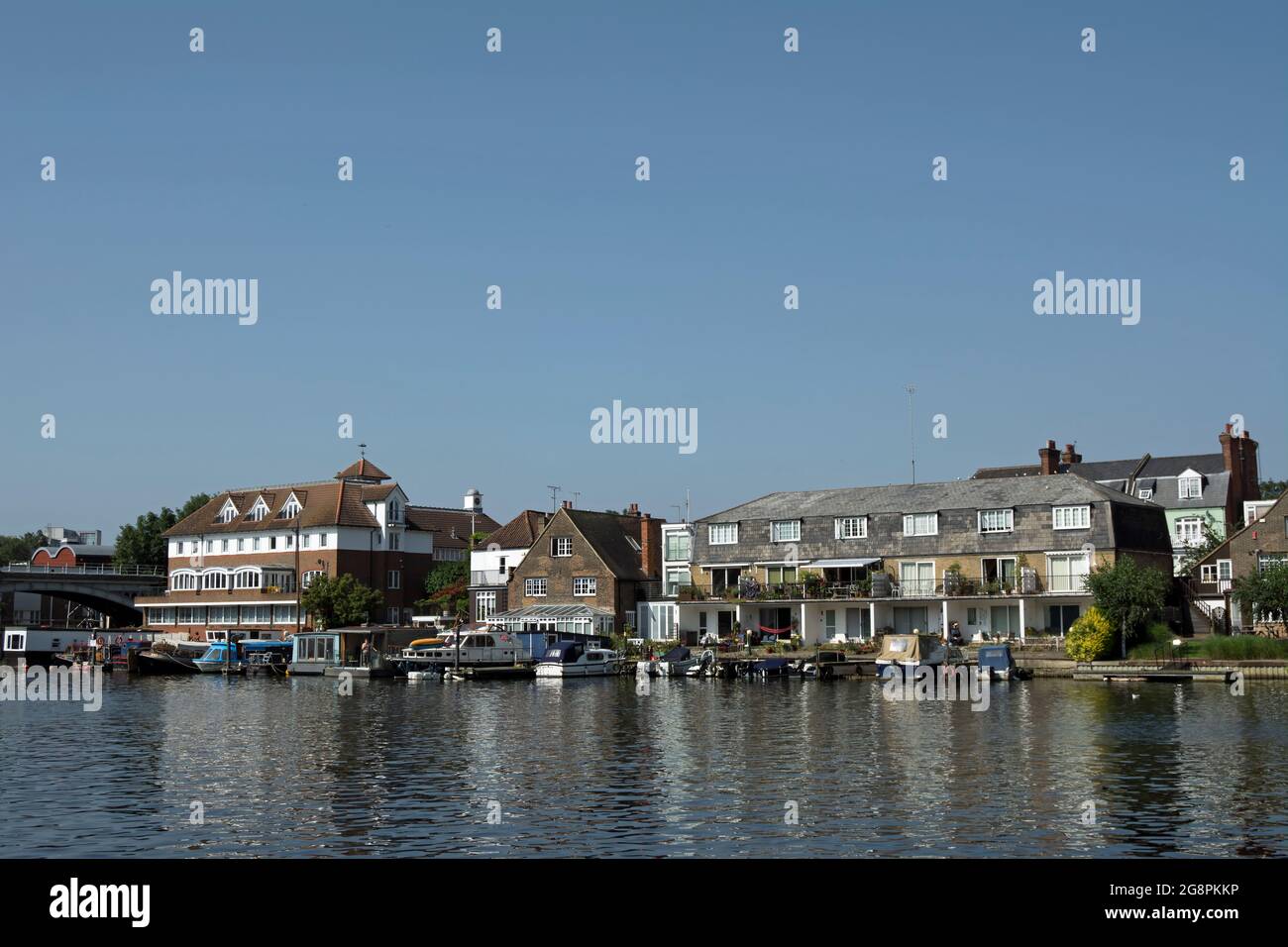 summer view across the river thames from canbury gardens towards the houses and moored boats of hampton wick, southwest london, england Stock Photo