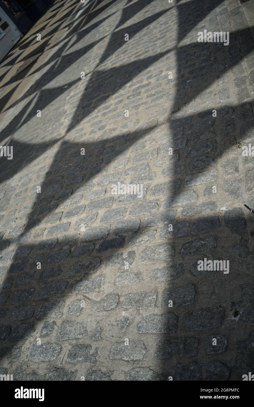 shadows of triangular flags on a cobbled street Stock Photo