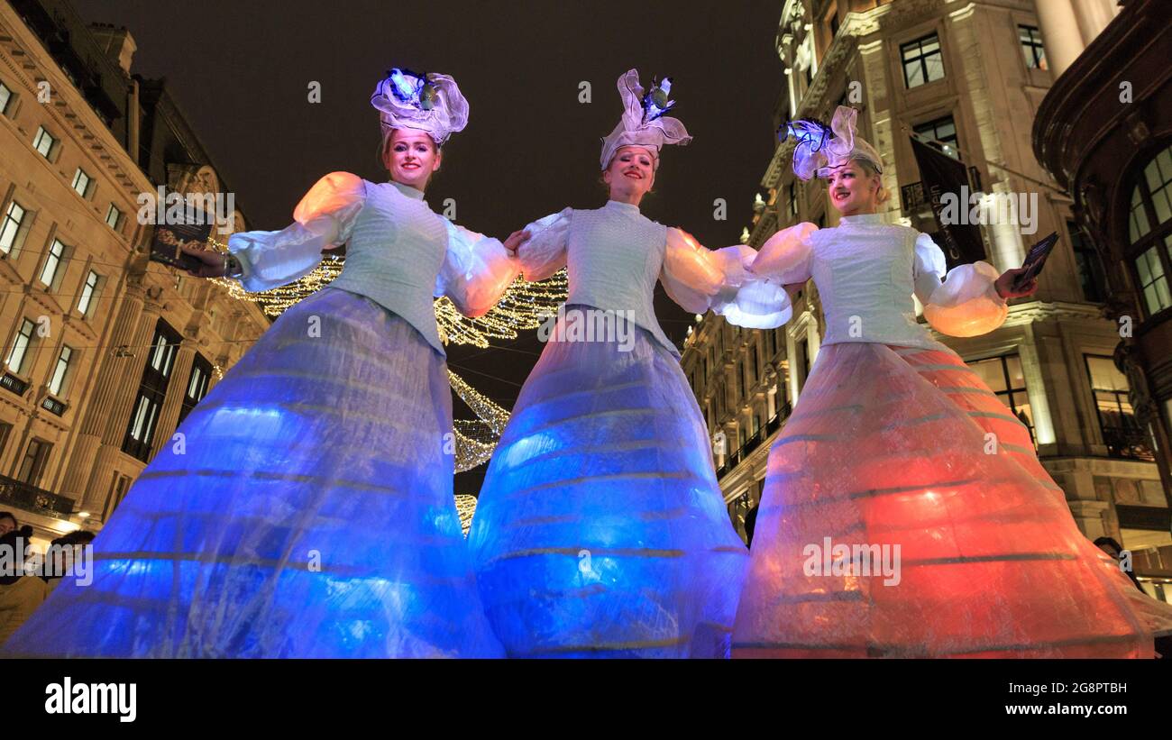 Stilt dancers perform in illuminated dresses at the Regent Street Christmas Lights switch on, London, England Stock Photo