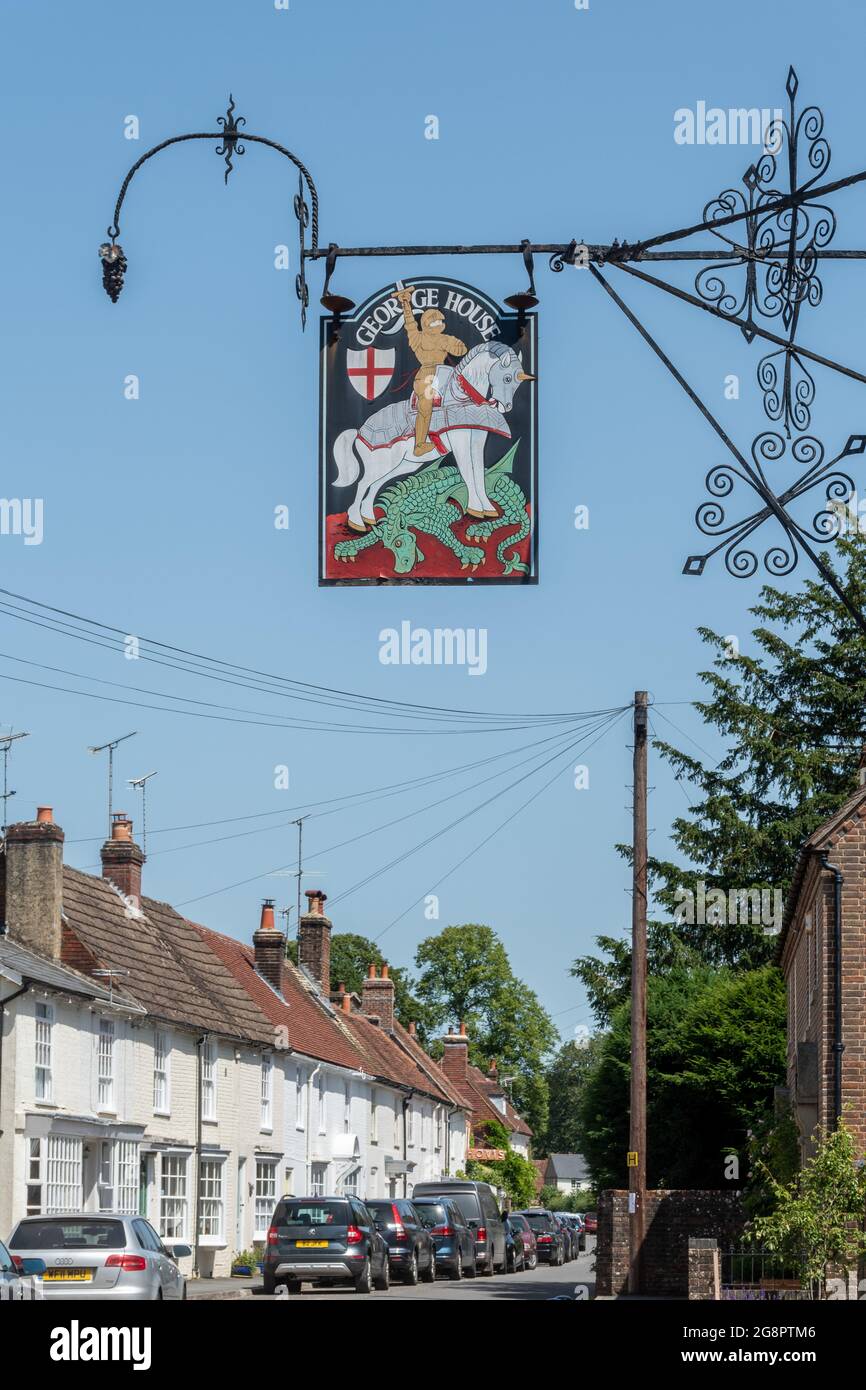 George House pub sign on an ornate wrought-iron bracket in the Hampshire village of Hambledon with St George and the Dragon, England, UK Stock Photo