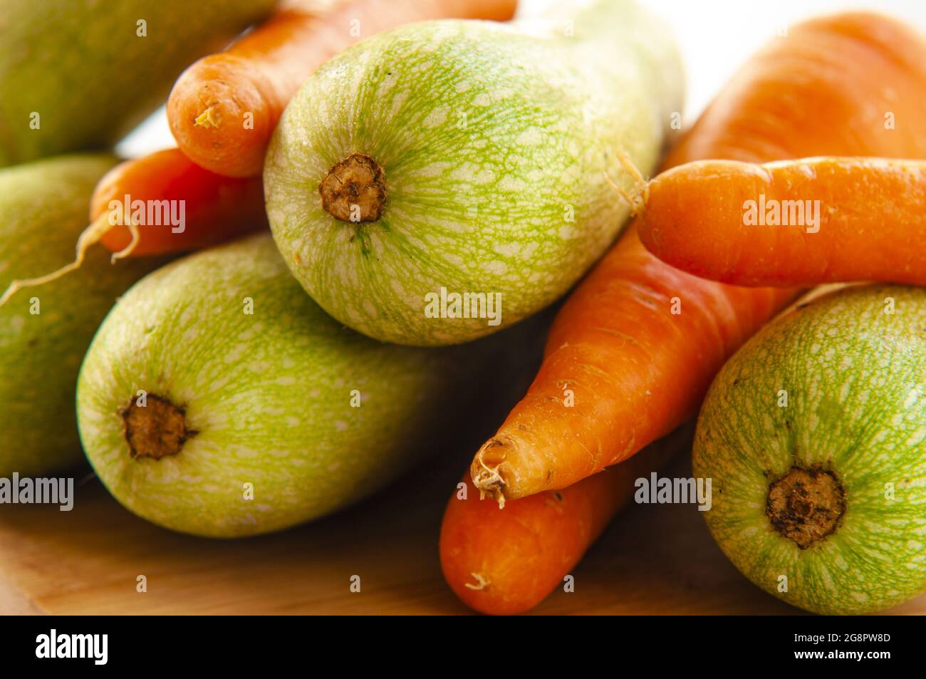 Closeup of freshly picked carrots and zucchinis placed together on a wooden surface Stock Photo