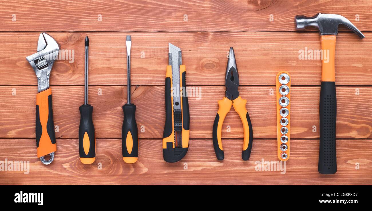 Set of construction tools on a brown wood table. Hammer, wrench, pliers and screwdriver. Postcard for the holiday Labour Day. Equipment, workplace. Fl Stock Photo