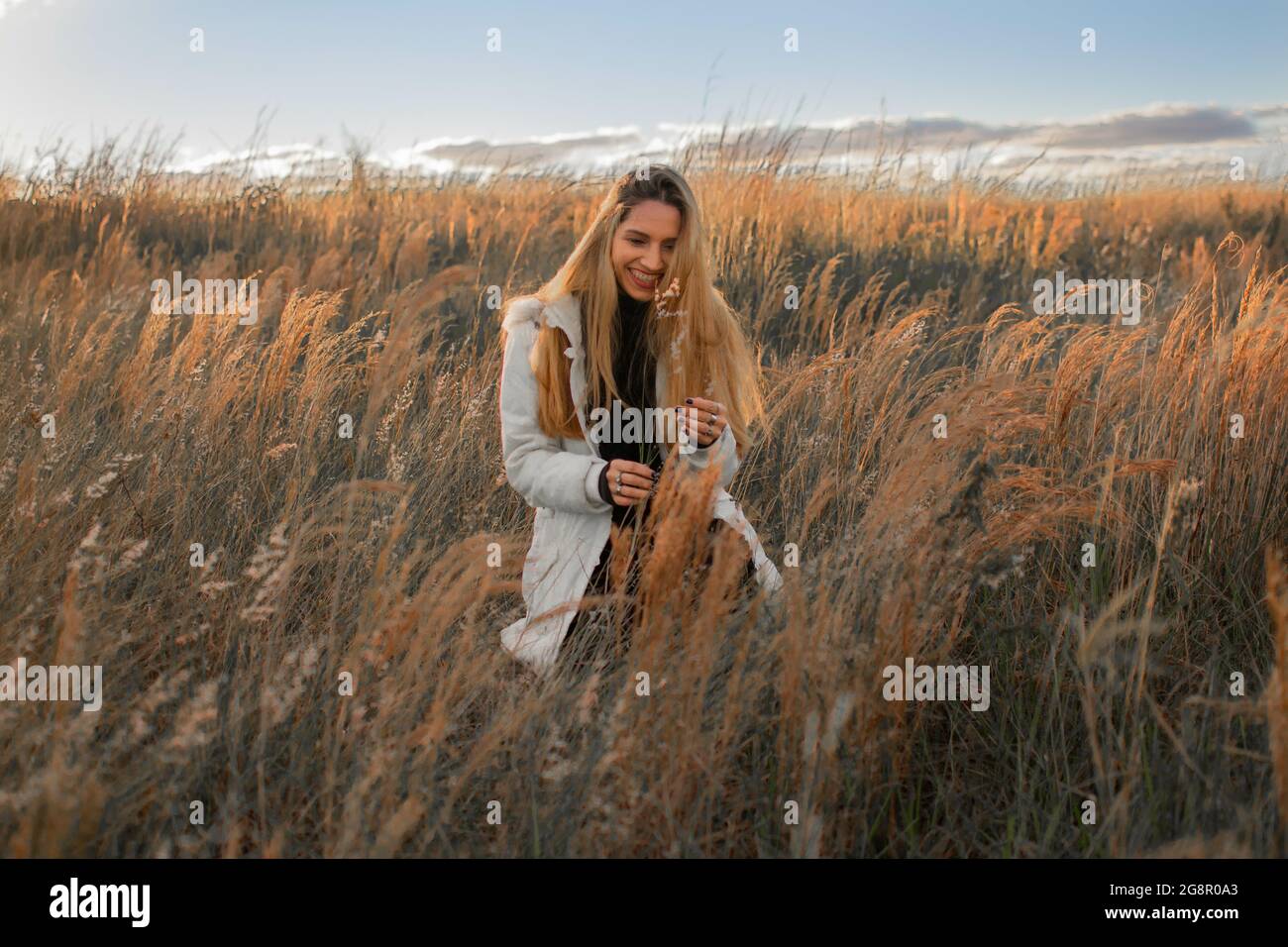 Young blonde-hair Hispanic female having a nice time in the field at sunset  Stock Photo - Alamy