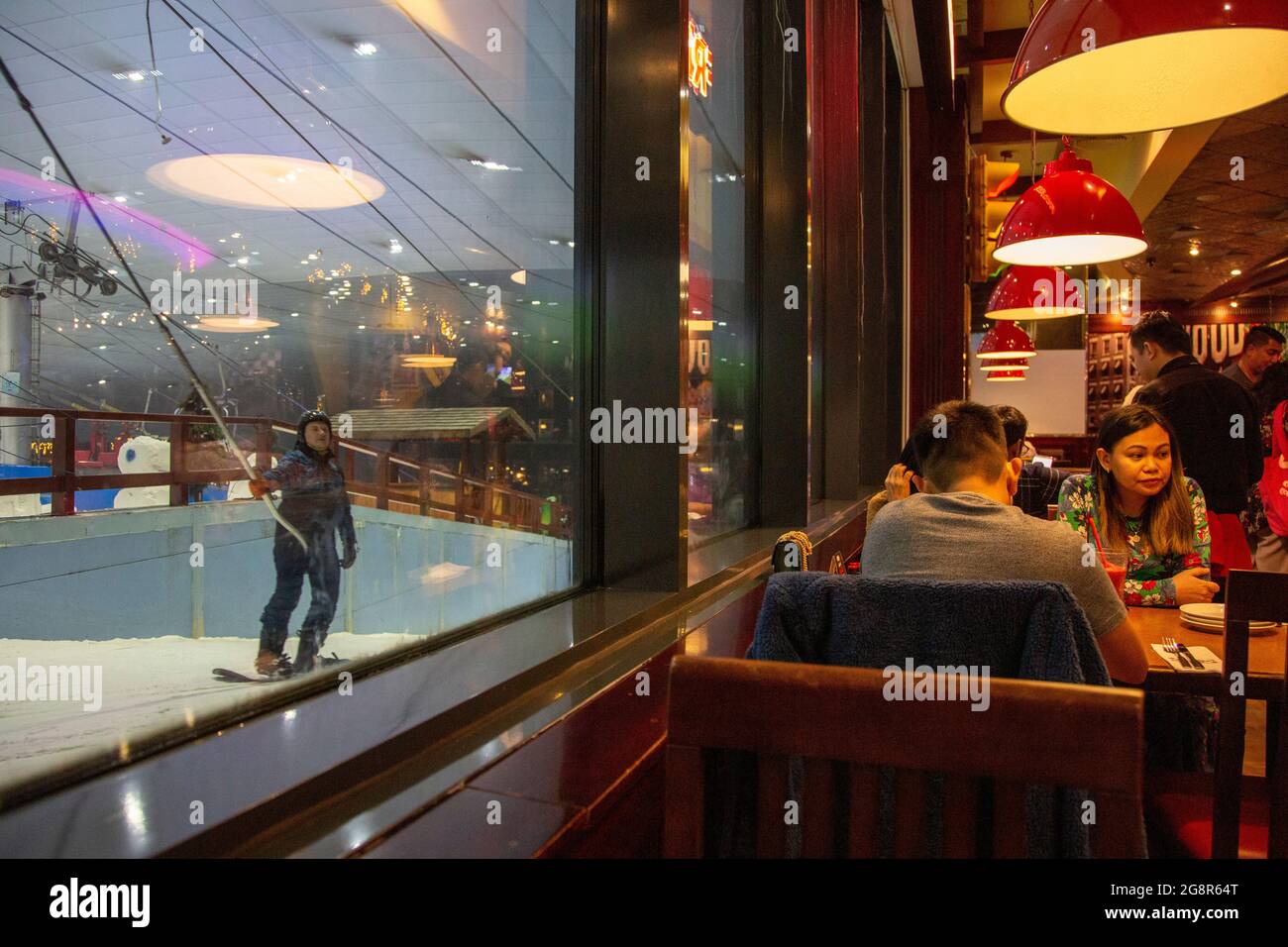 Diners at TGI Friday's at the Mall of the Emirates with a view of the ski slopes of Ski Dubai, Dubai, UAE. --- Ski Dubai is an indoor ski resort with Stock Photo