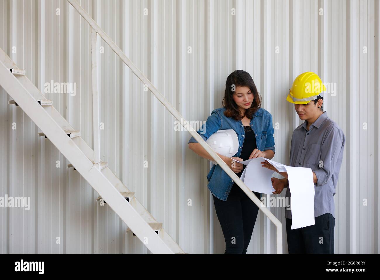 Two Asian engineers, man and woman, discussing in construction site Stock Photo