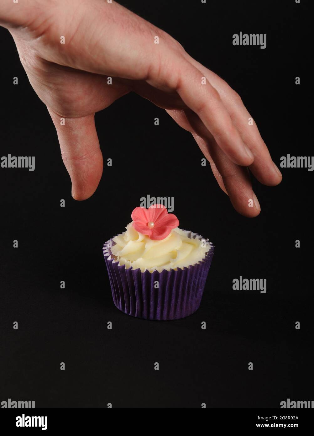 The last cupcake about to be grabbed on black background. fairy cake cakes fancy Stock Photo