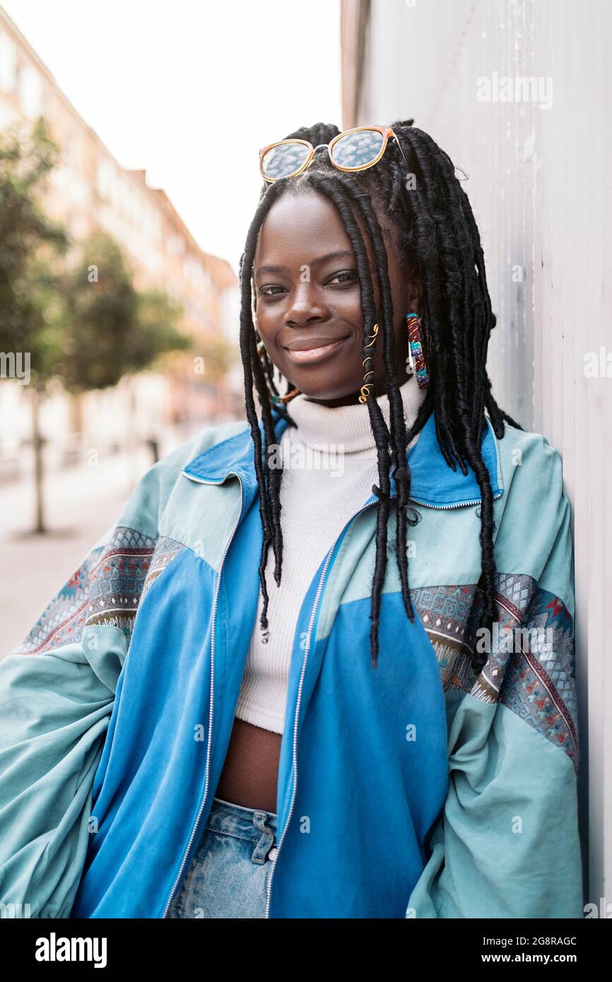 Happy and young african woman with cool braids smiling and looking at ...